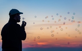 Мужчина пускает мыльные пузыри на закате