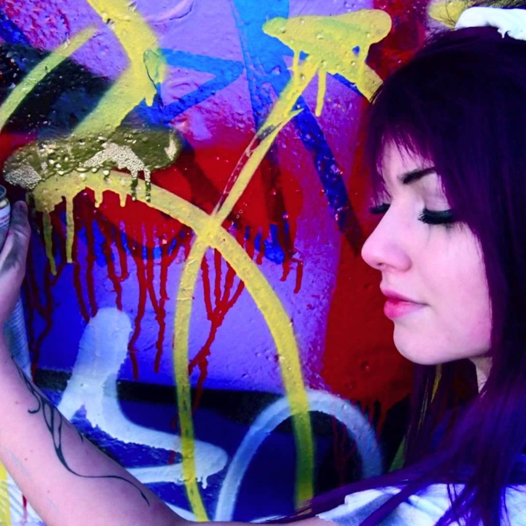 Девушка рисует граффити на стене