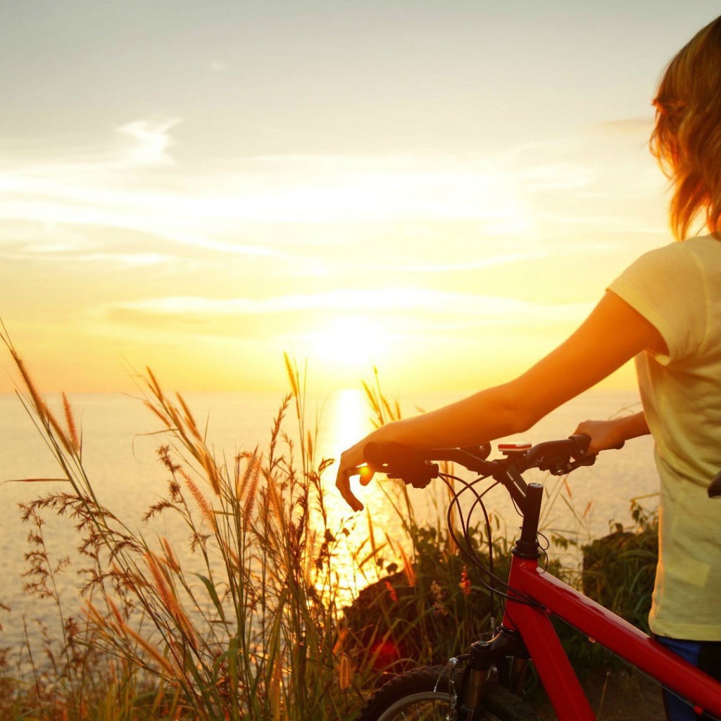 Девушка с велосипедом смотрит на закат