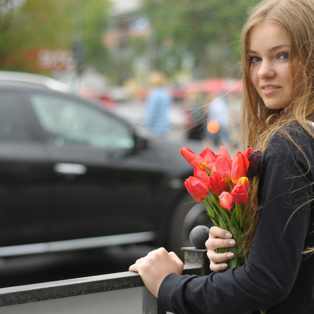 Девушка с букетом тюльпанов стоит у забора