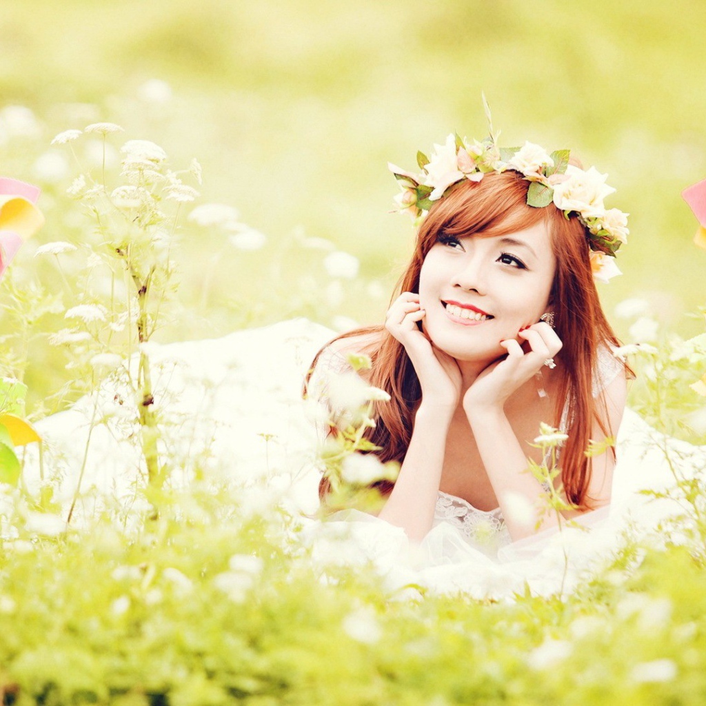 Рыжая японская девушка лежит в поле цветов