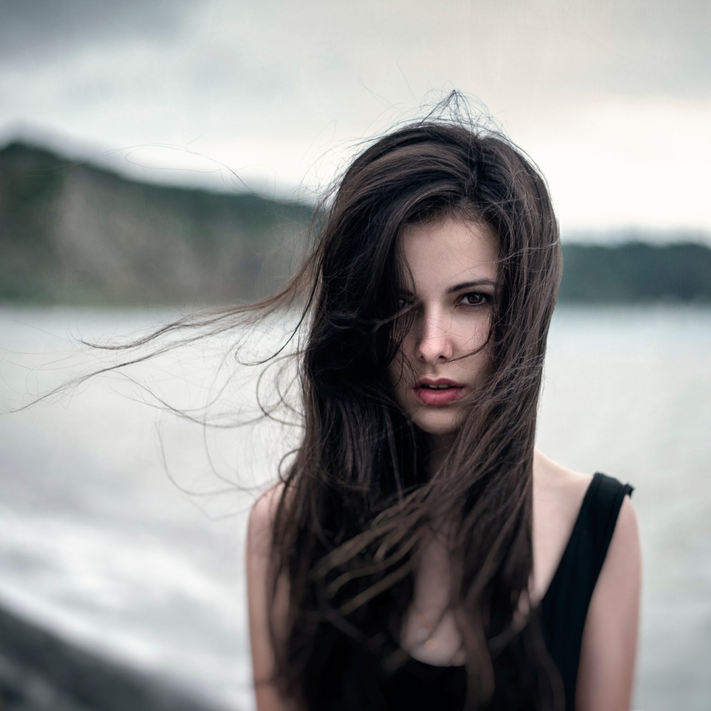 Ветер треплет волосы девушки у моря, портрет