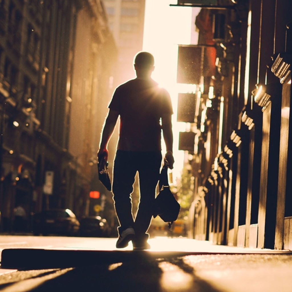Мужчина идет по улице навстречу солнцу