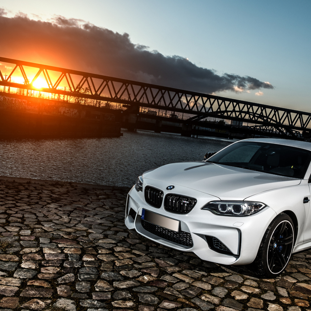 Белый автомобиль BMW M2 на фоне заката 