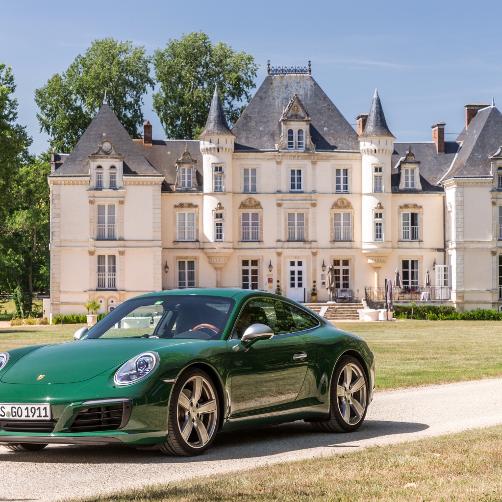 Green sports car Porsche 911 Carrera on the background of the house