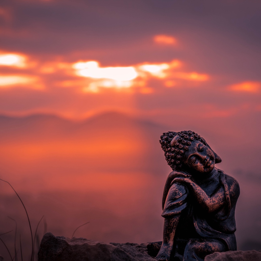 Статуя Будды на фоне солнца на закате