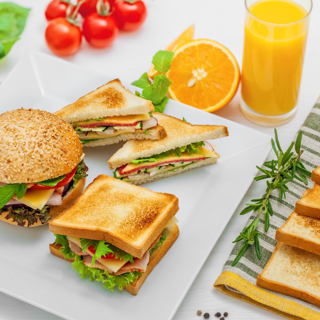 Гамбургер и сендвичи на столе с апельсиновым соком