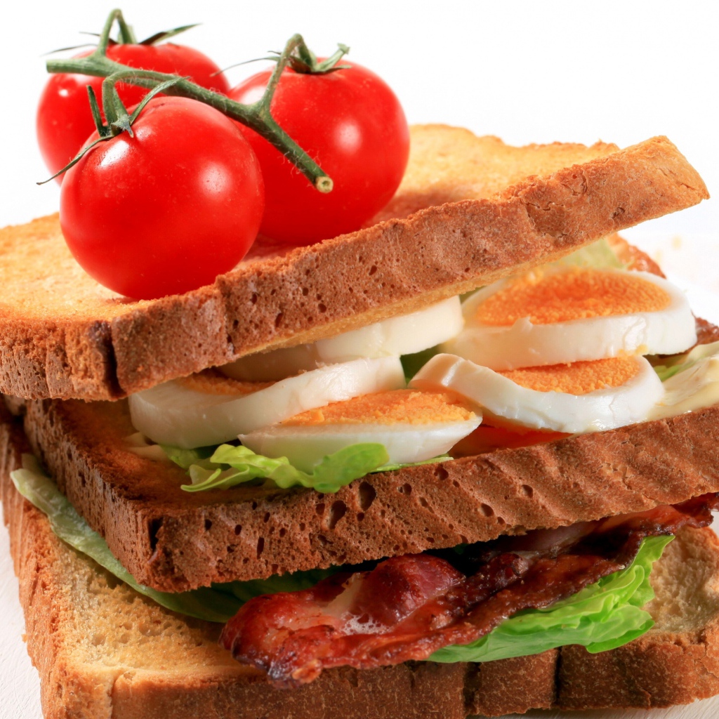 Сэндвич с беконом, яйцами и овощами на белом фоне