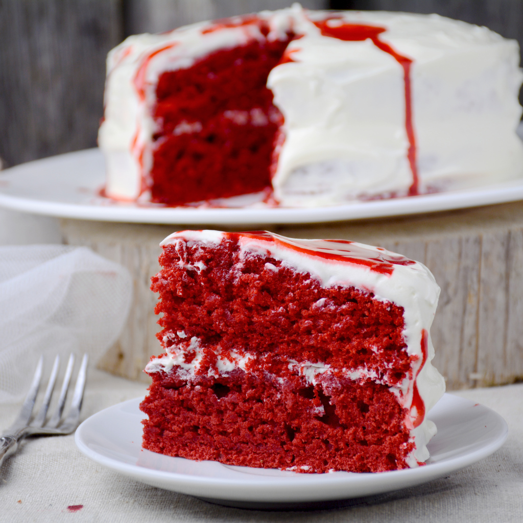 Кусок торта красного цвета с белым кремом 