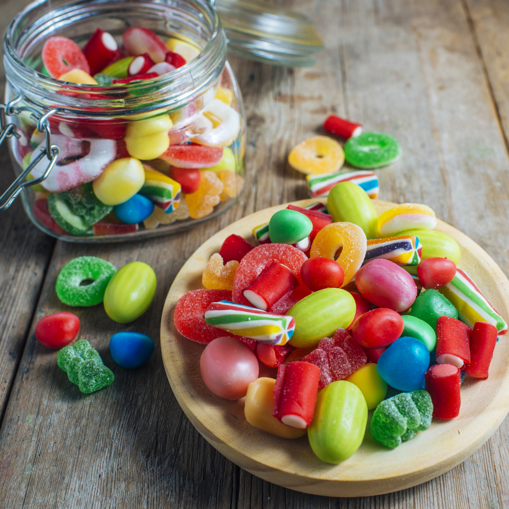 Разноцветные мармеладные конфеты в стеклянной банке на столе