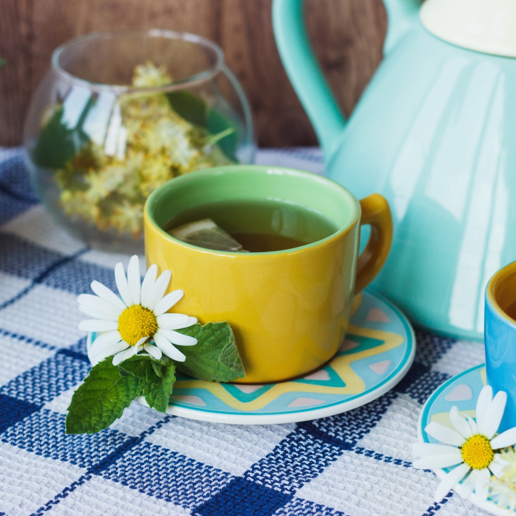 Tea with chamomile flowers in a yellow cup on the table