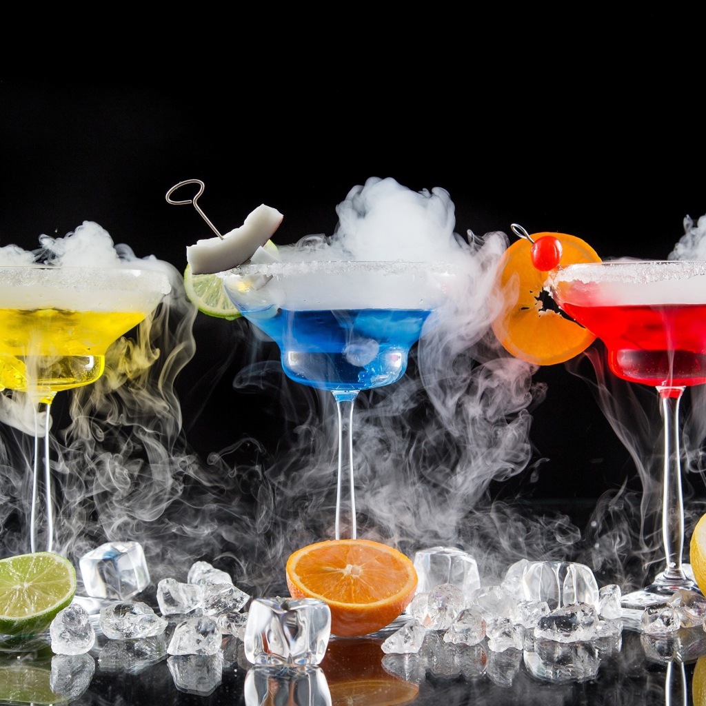Три алкогольных коктейля с сухим льдом на черном фоне