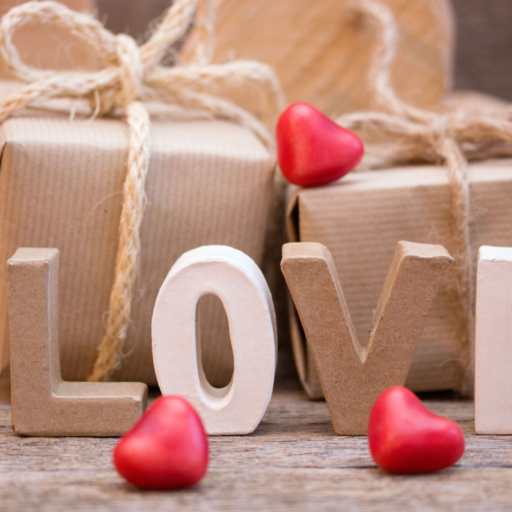 Романтические подарки и надпись Love с красными сердечками
