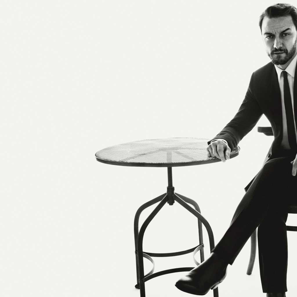 Актер Джеймс Макэвой сидит на стуле за столом черно-белое фото