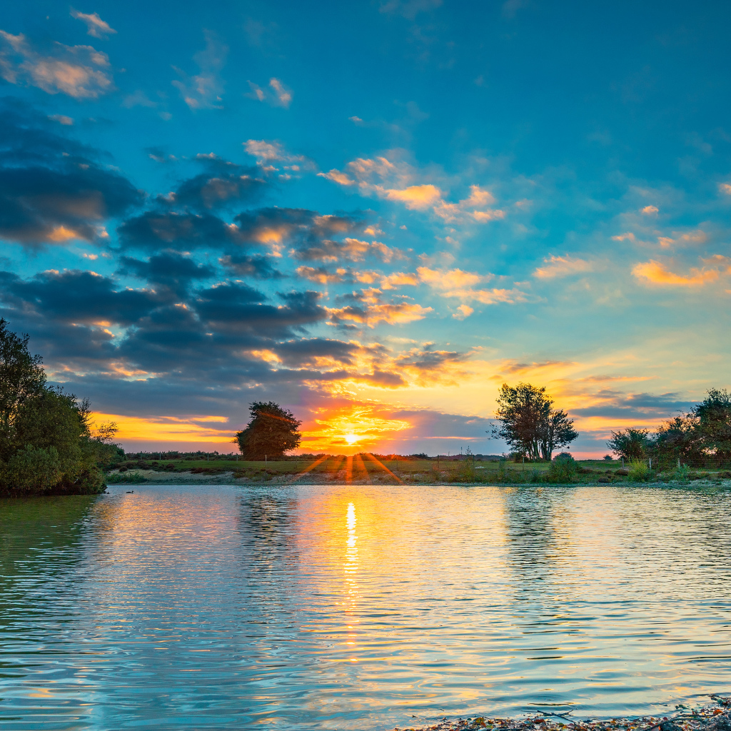 Закат солнца в небе отражается в воде озера 