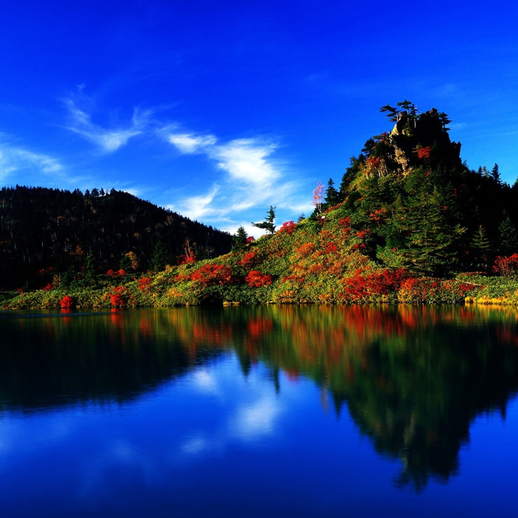 Голубое небо отражается в чистой воде озера 
