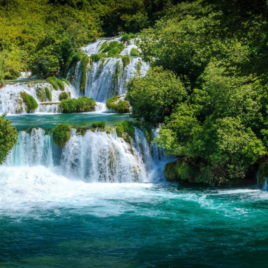 Бушующая голубая вода водопада у зеленых деревьев
