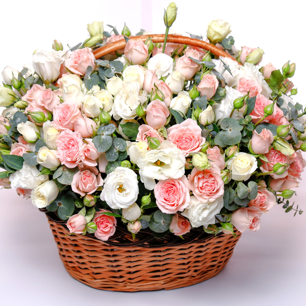 Корзина с красивым букетом цветов роз, эустомы на розовом фоне