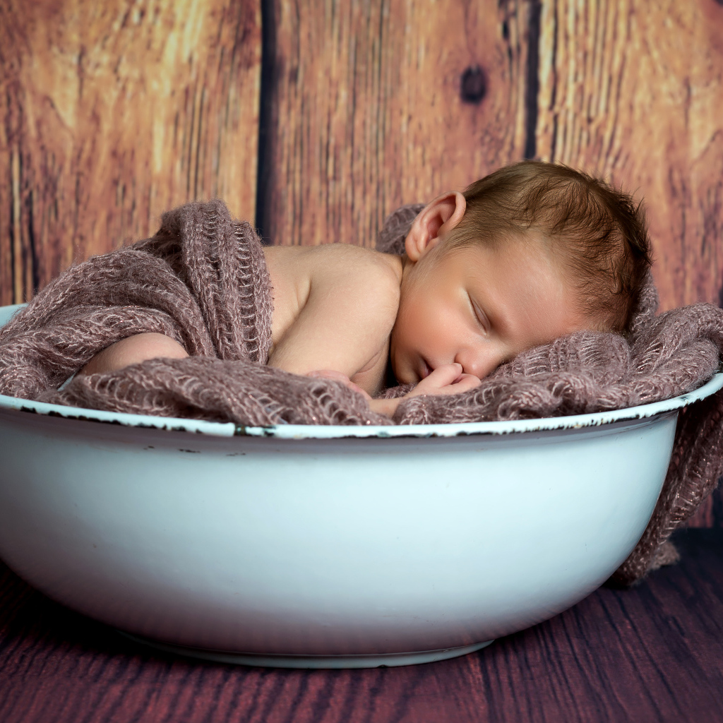 Новорожденный ребенок спит в белой миске