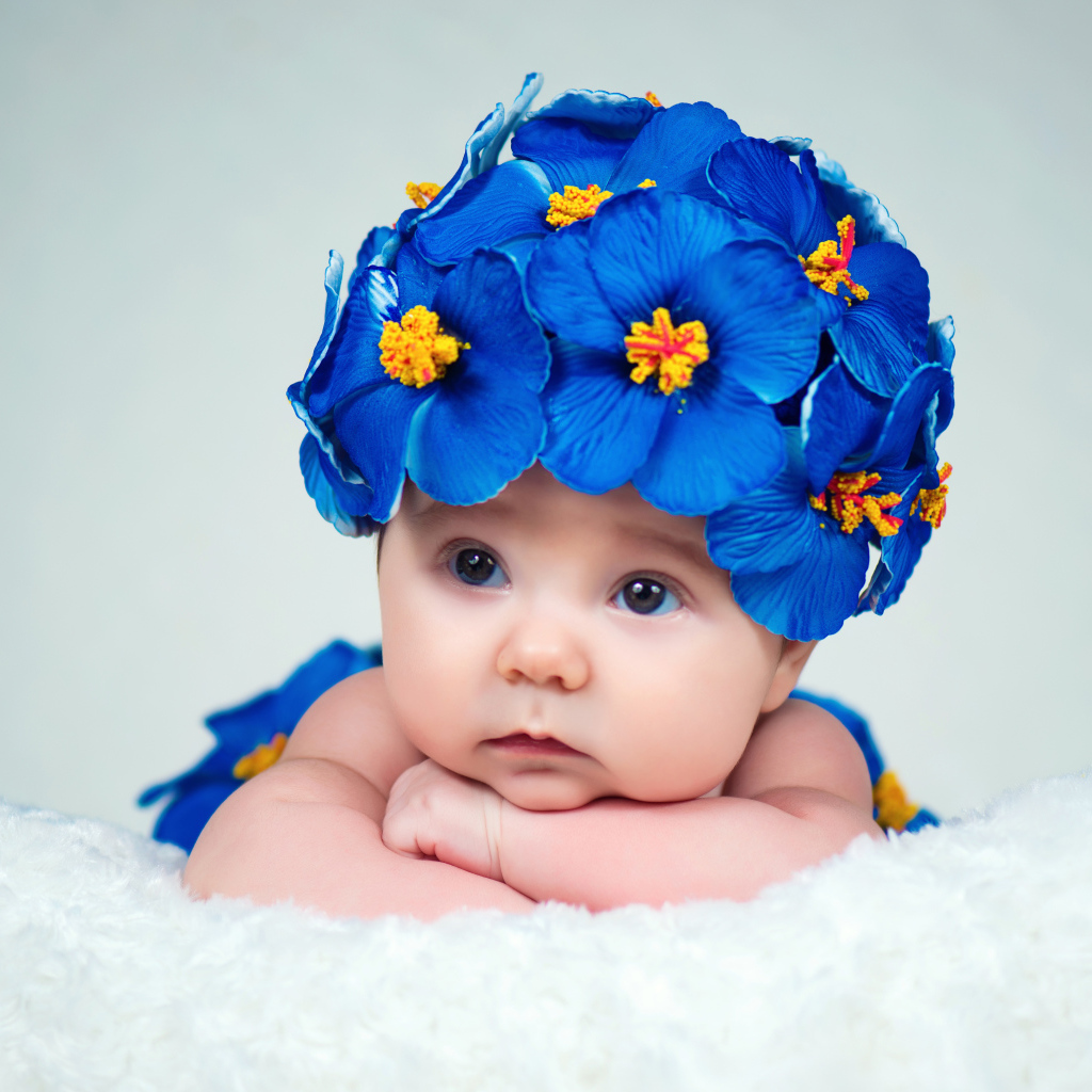 Маленький ребенок в красивой шапке с голубыми цветами