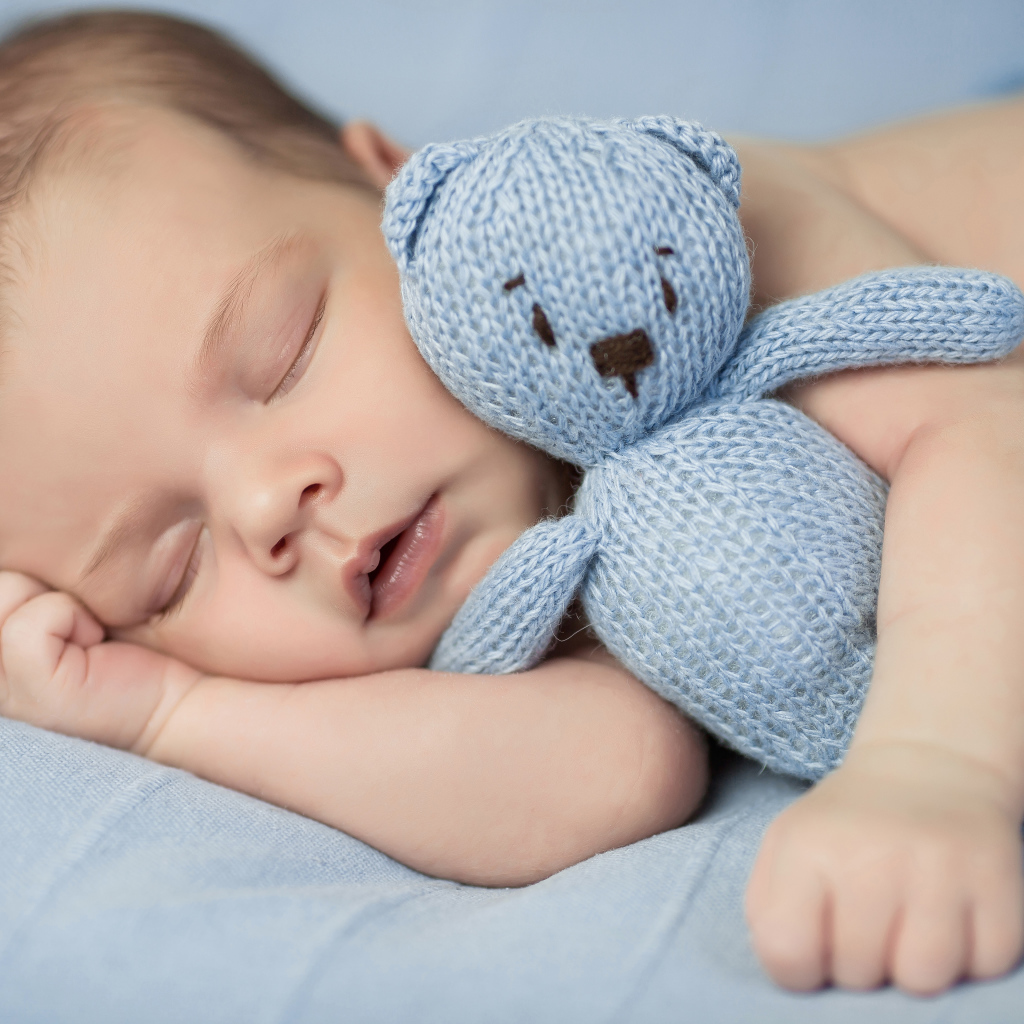 Милый спящий младенец с вязаной мягкой игрушкой