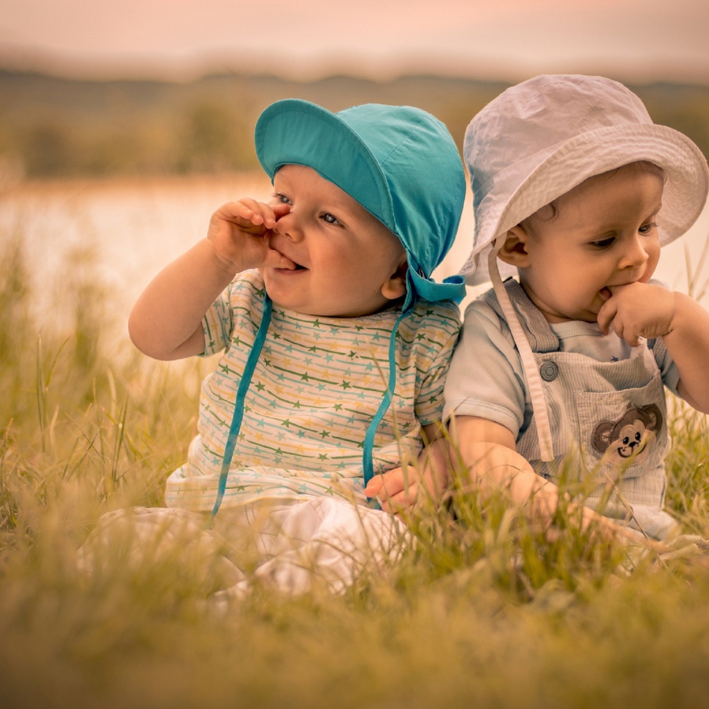 Два милых малыша в зеленой траве летом 