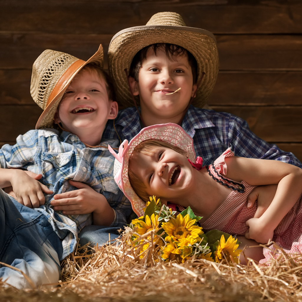 Два улыбающихся мальчика и девочка в соломенных  шляпах