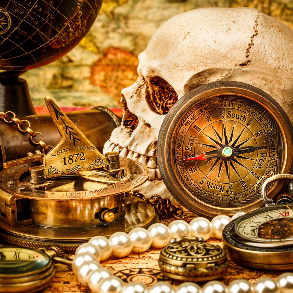 Череп, бинокль, компас, жемчуг и старинные часы на столе