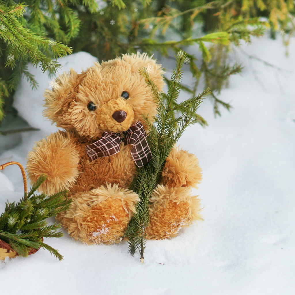 Плюшевый медвежонок на снегу с еловыми ветками
