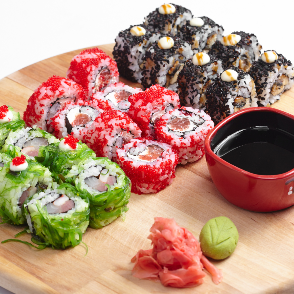 Different appetizing sushi on a wooden board with soy sauce