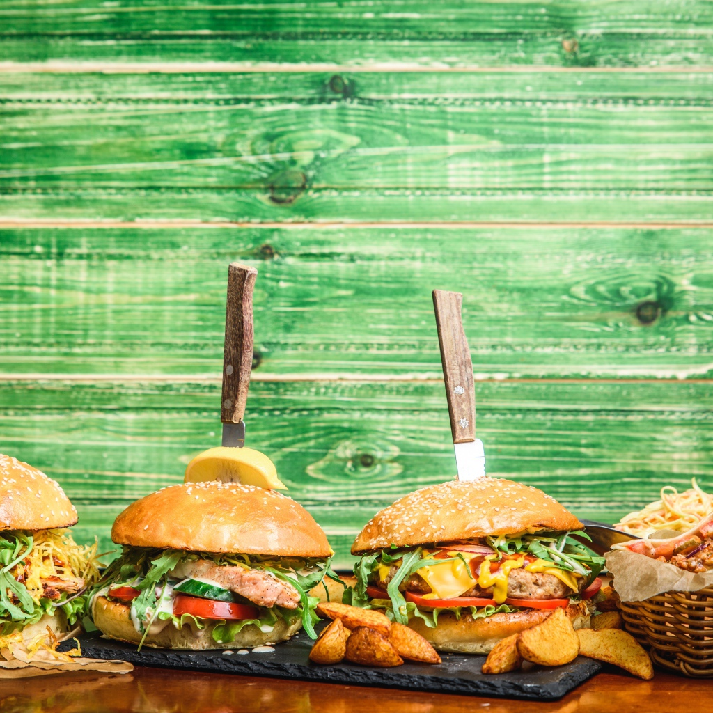 Гамбургеры с ножами на деревянном фоне