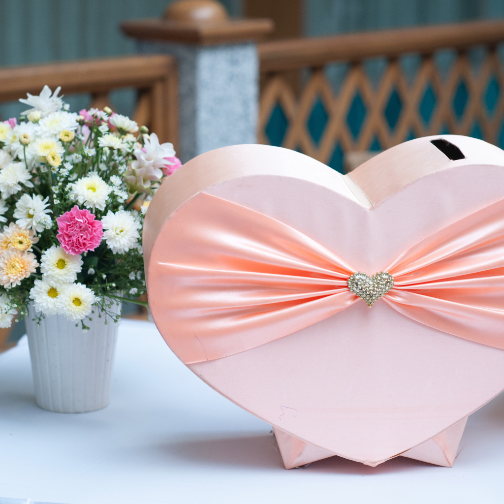 Большая розовая коробка в форме сердца на столе с букетом хризантем