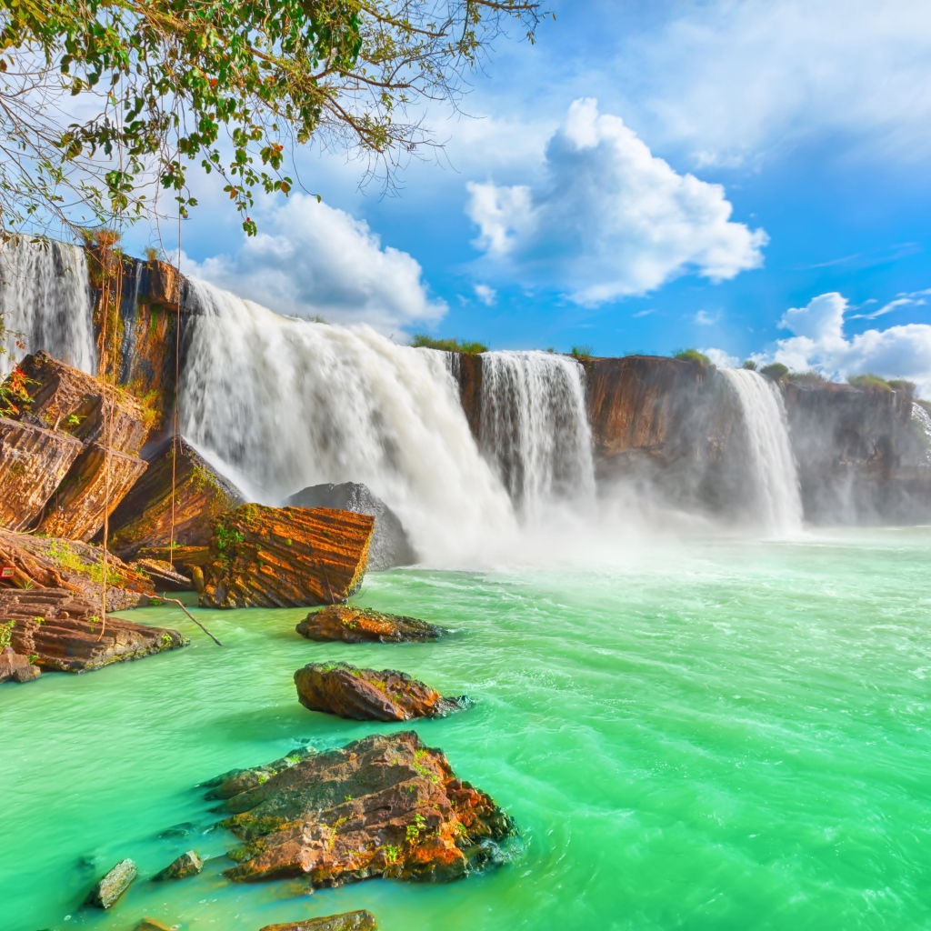 Быстрый водопад стекает со скалы под красивым голубым небом