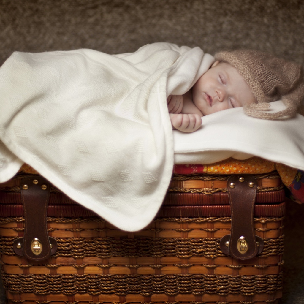 Грудной ребенок спит на плетеной корзине