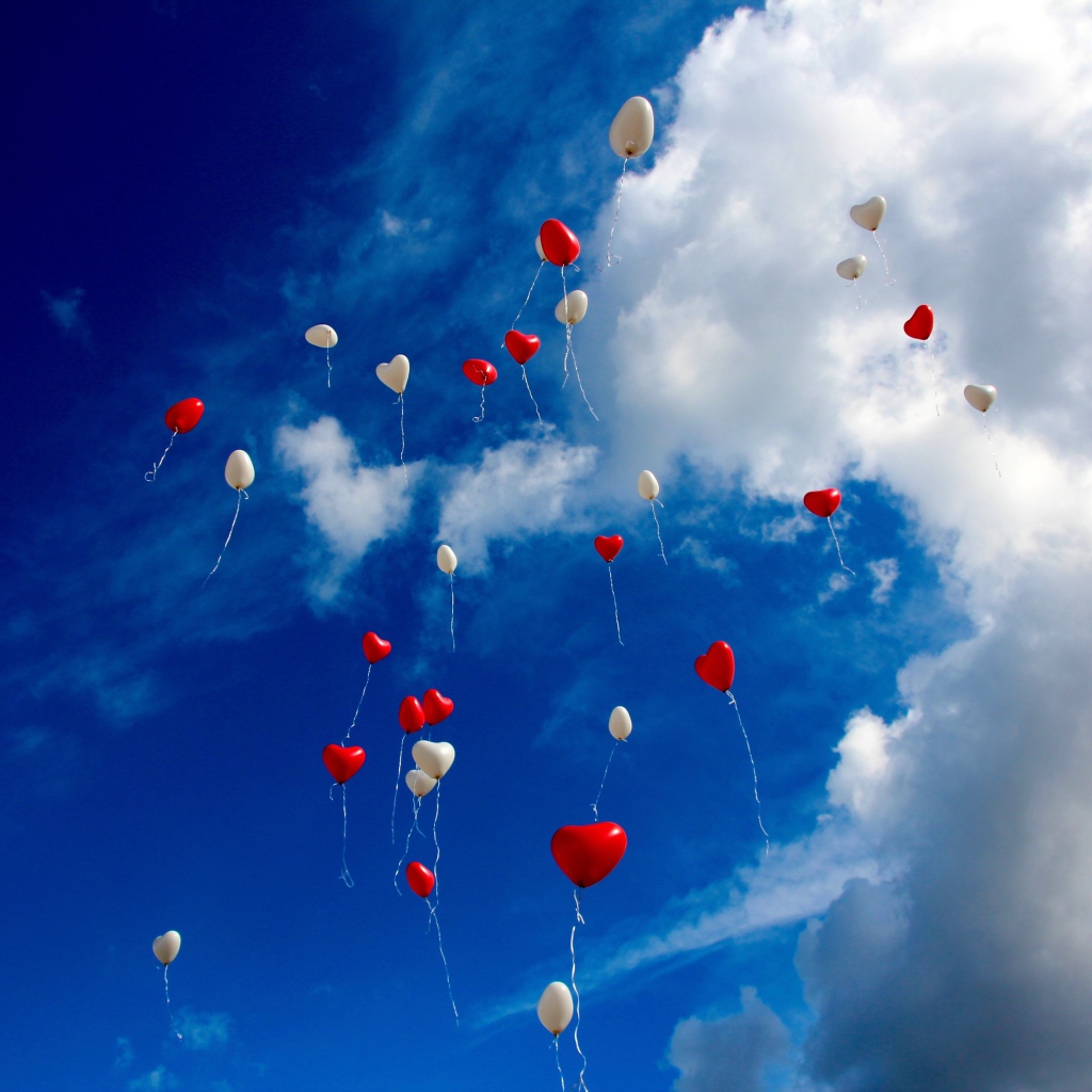 Много шариков в форме сердца в небе с белыми облаками