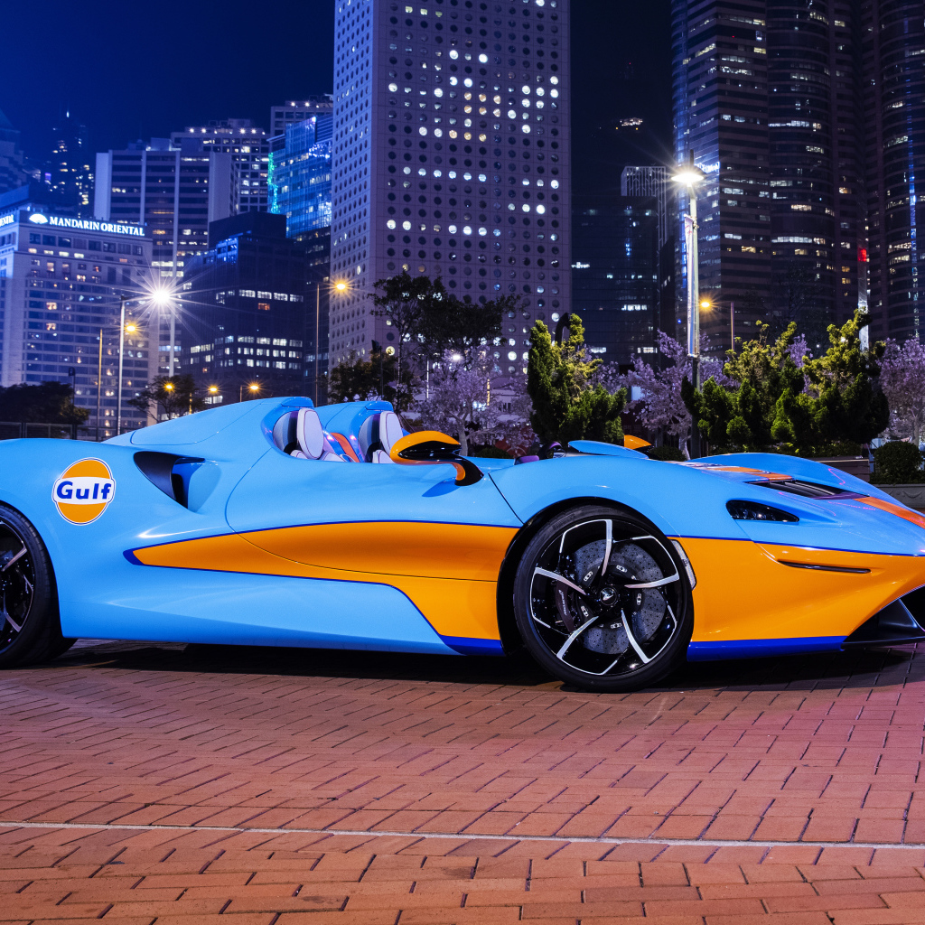 Автомобиль McLaren Elva Gulf Theme, 2021 года на фоне города