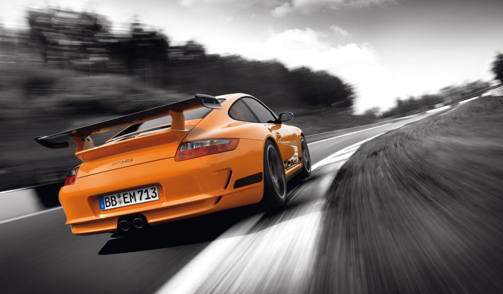 Оранжевый Porsche GT3RS на сером шоссе