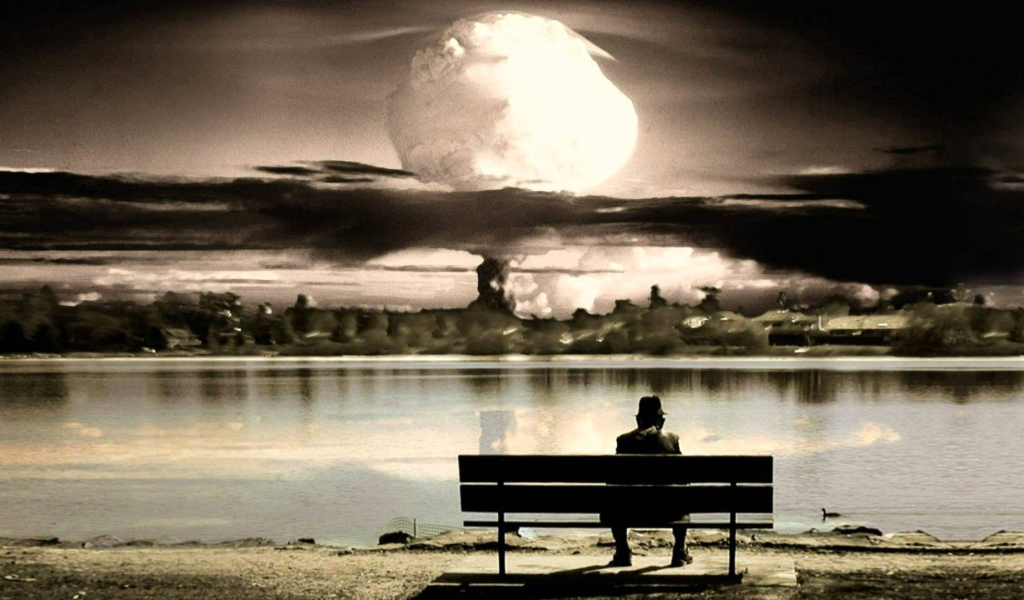 Человек смотрит на ядерный взрыв сидя на скамье