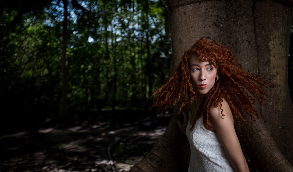 Рыжая девушка с кудрями у большого дерева