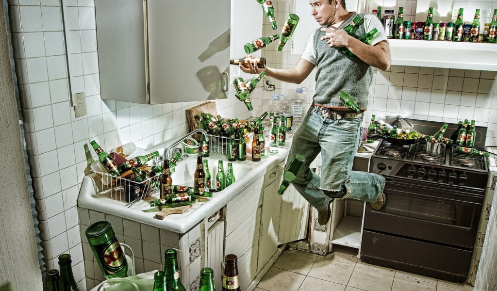 Мужчина среди бутылок пива на кухне