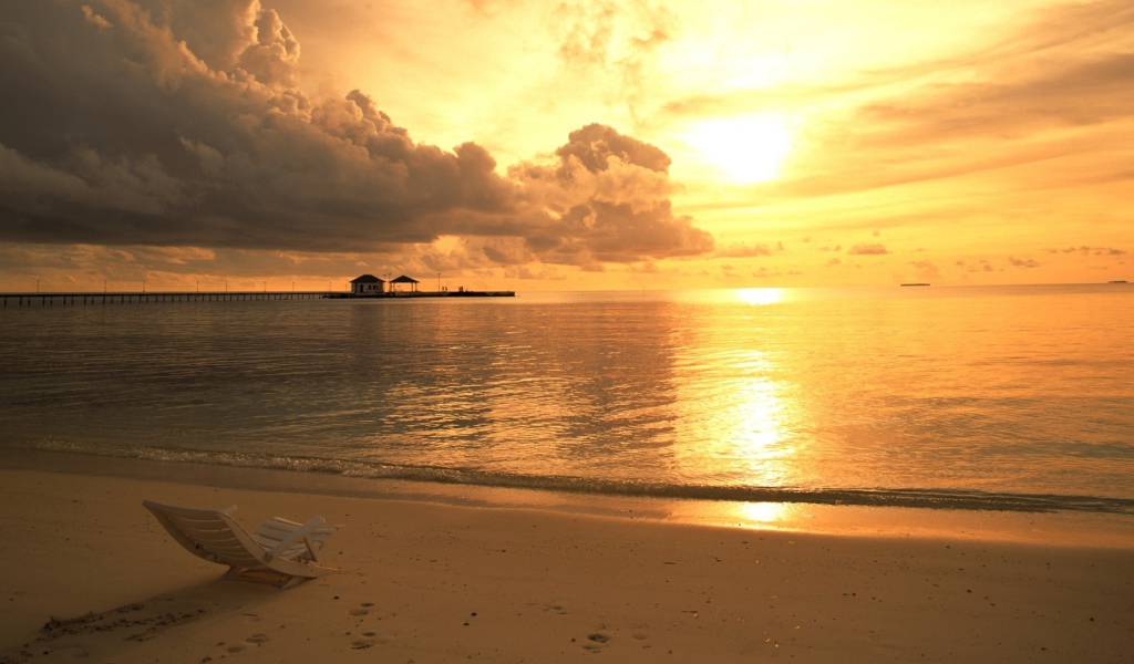 Одинокий шезлонг на пляже на закате