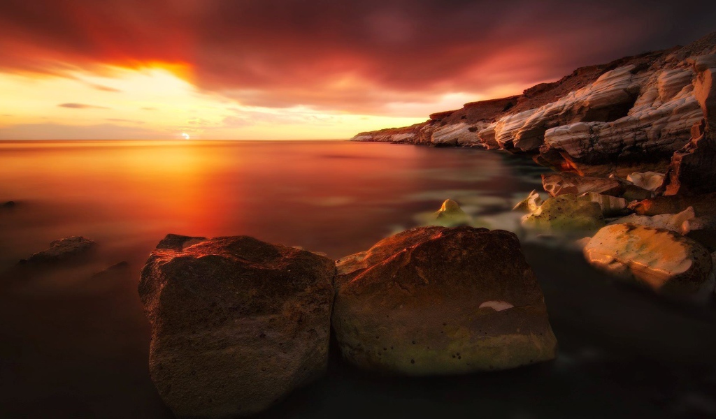 Два больших камня на берегу моря на закате