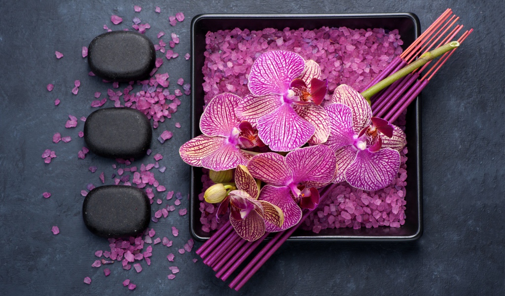 Цветы орхидеи с ароматическими палочками, камнями и солью