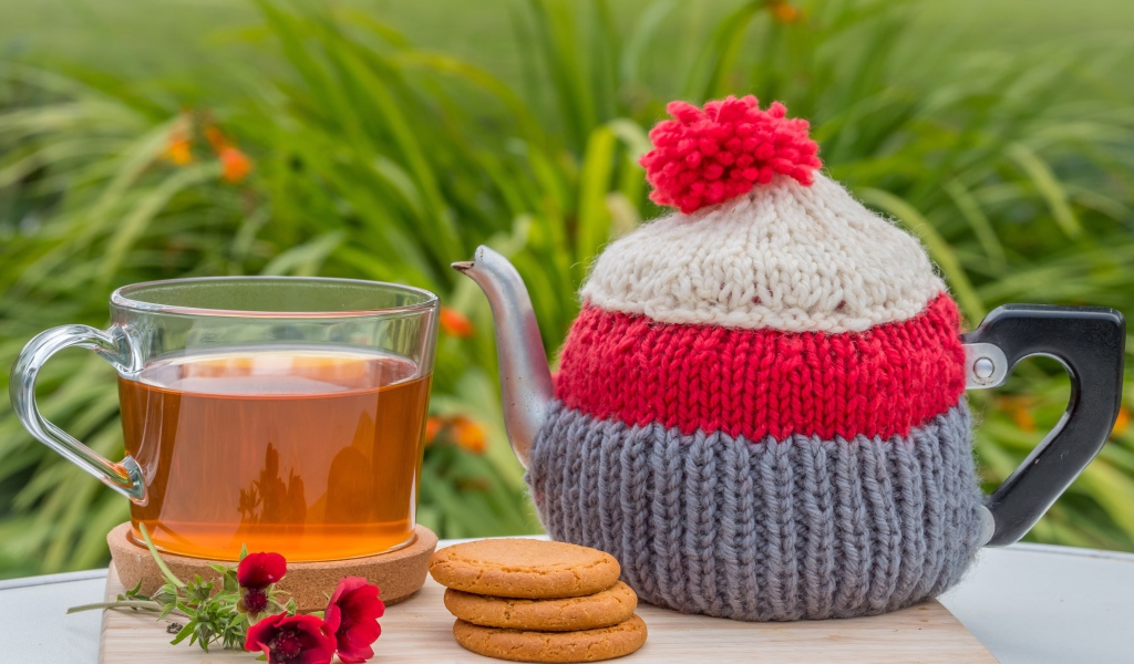 Чайник с чашкой чая на столе с печеньем и цветами