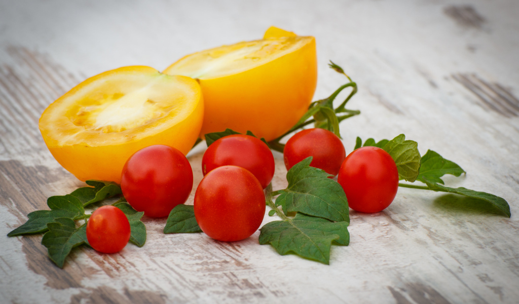 Желтые и красные помидоры на деревянной доске