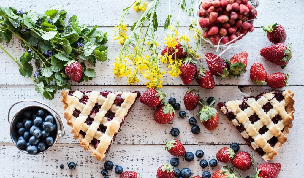 Кусочки пирога на столе с ягодами клубники и черники