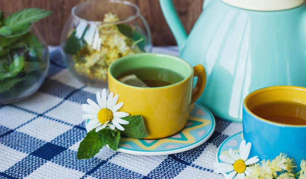 Tea with chamomile flowers in a yellow cup on the table