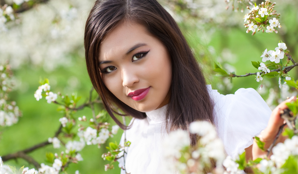 Красивая девушка азиатка в ветках цветущего дерева