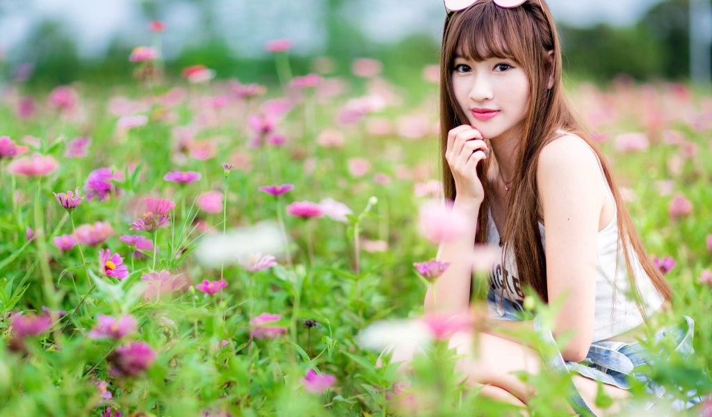 Красивая девушка модель азиатка на поле с розовыми цветами