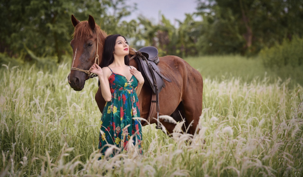 Красивая девушка азиатка с конем в поле
